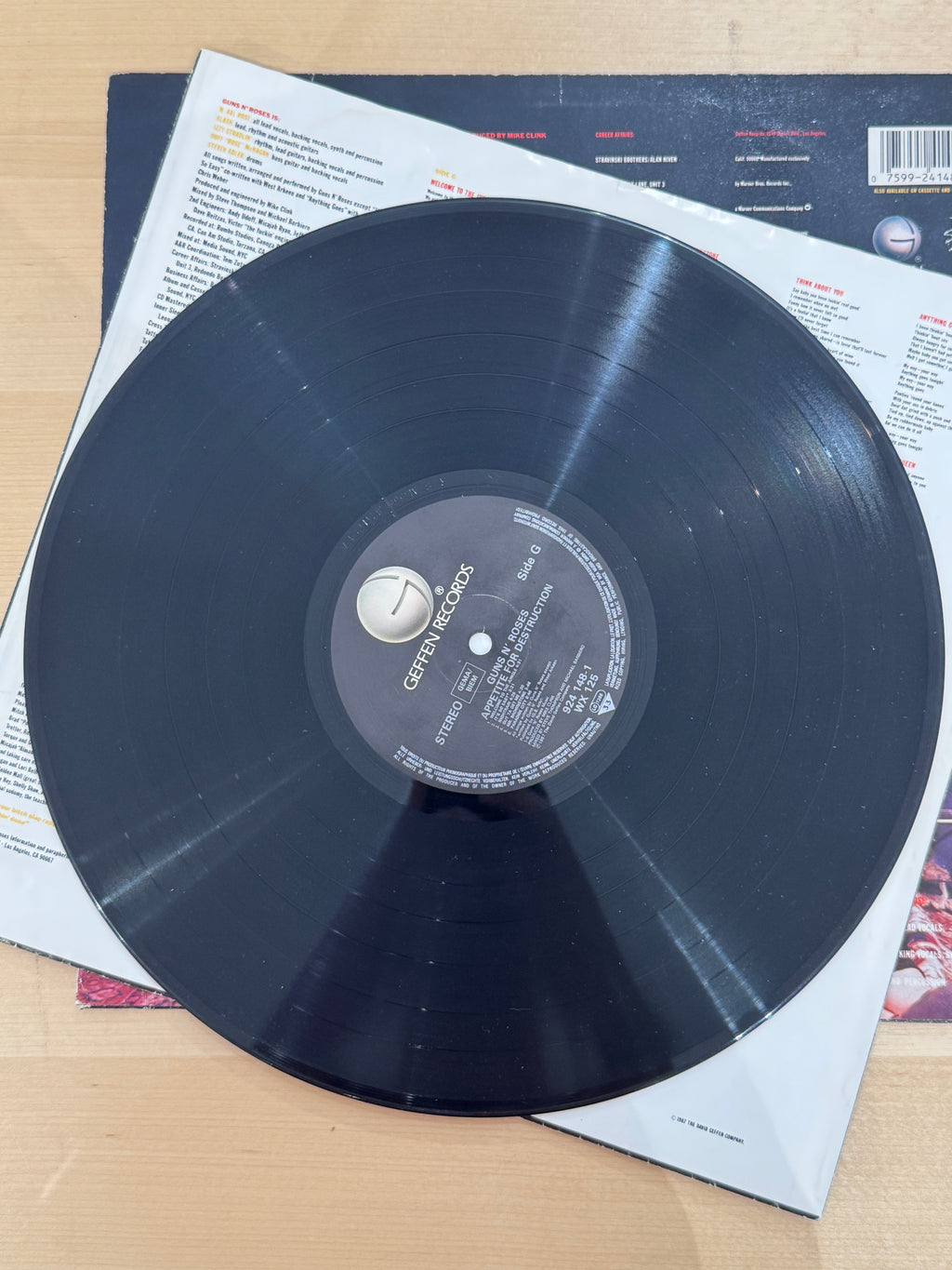 Guns N' Roses – Appetite for Destruction, etichetta vinile Side A: label nera Geffen Records, catalogo WX 125, titolo Appetite for Destruction, 33 giri Stereo, inner sleeve con testi visibile sullo sfondo