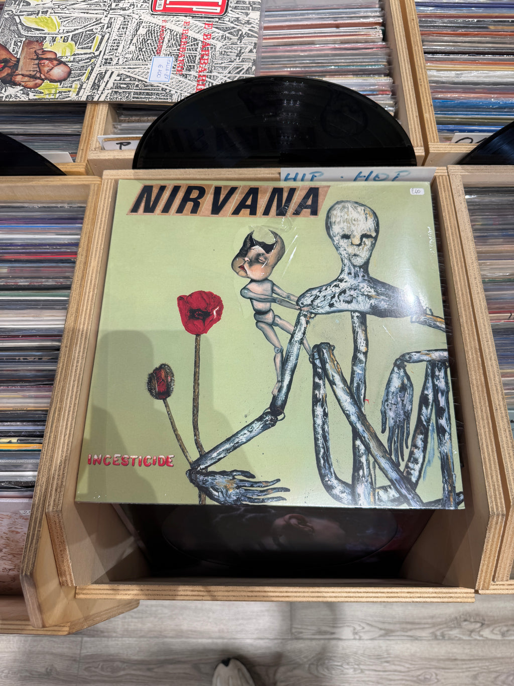 Dettaglio copertina Nirvana Incesticide - plastica protettiva con strappo visibile in alto, scritta HLP