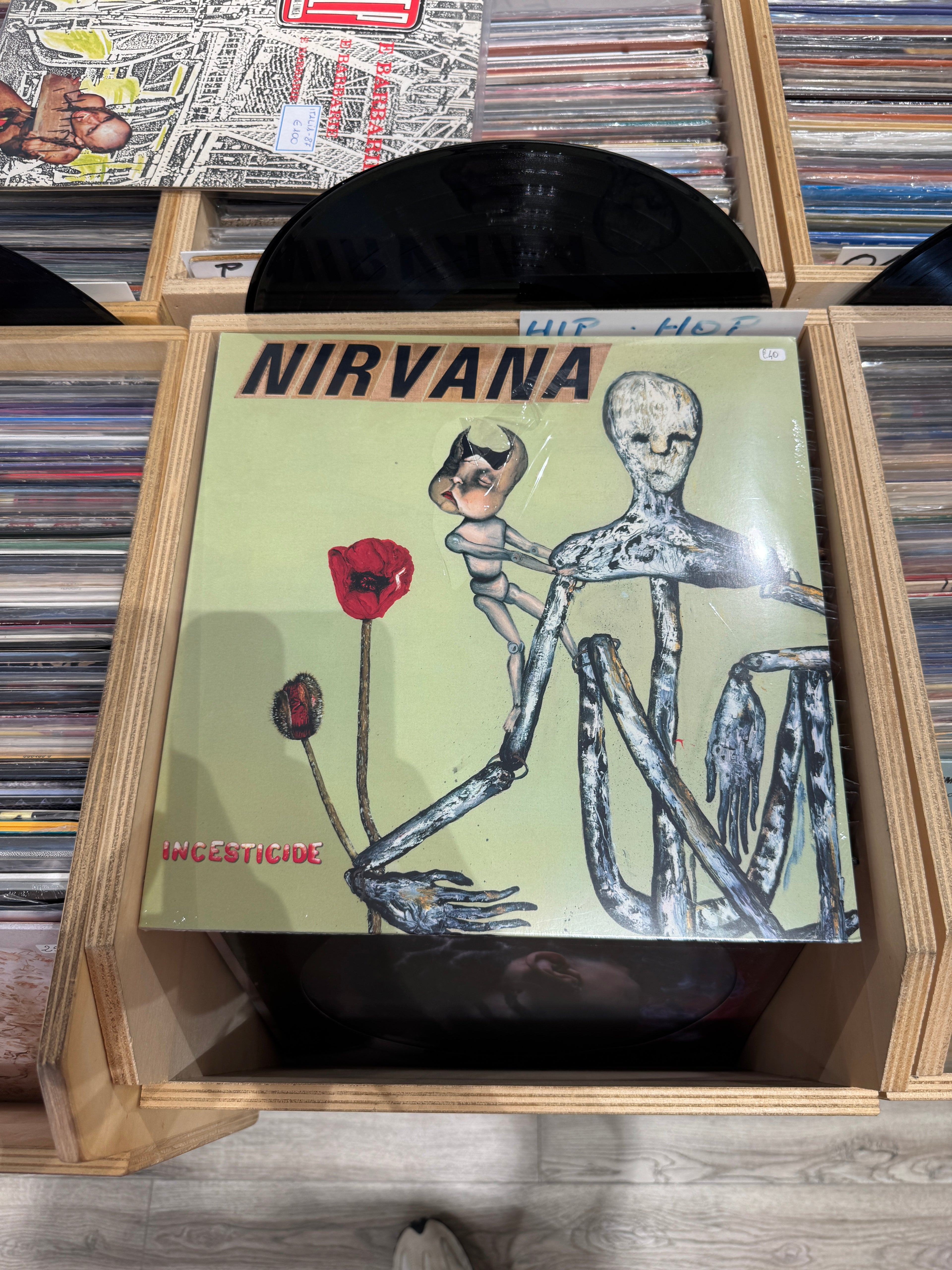 Dettaglio copertina Nirvana Incesticide - plastica protettiva con strappo visibile in alto, scritta HLP